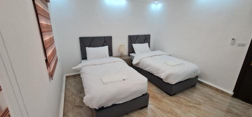 two beds in a small room with white sheets at Nabateans Home Hotel in Wadi Musa
