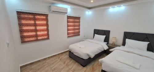 two beds in a room with white walls and windows at Nabateans Home Hotel in Wadi Musa