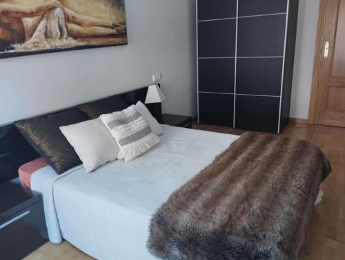 a bedroom with a white bed with a faux fur blanket at Precioso piso con ducha hidromasaje VUT-LE-726 in Astorga