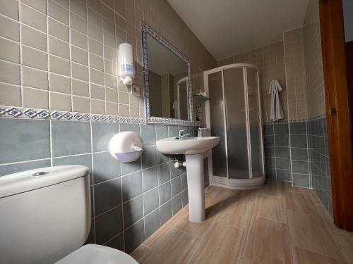 a bathroom with a toilet and a sink and a mirror at Hostal Parador de los Llanos in Torreorgaz