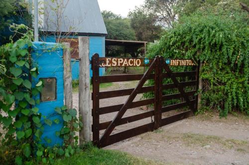 un cancello in legno con recinzione e casa blu di Espacio Infinito a Capilla del Monte