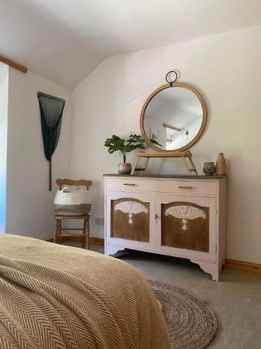 a bedroom with a dresser with a mirror on it at The Fishermans Cottage in Llanystumdwy