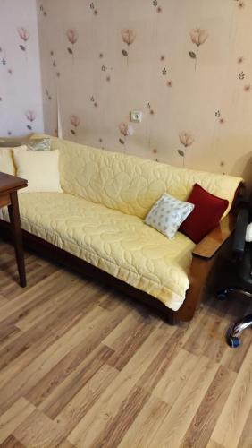 a yellow couch in a living room with flowers on the wall at Rami nakvynė Panevėžyje in Panevėžys