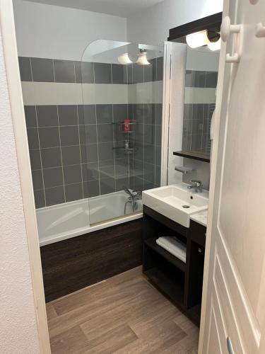 uma casa de banho com uma banheira, um lavatório e um chuveiro em La foux d allos Superbe appartement 6 couchages ,piscine em Allos