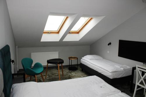 a room with two beds and a tv and skylights at Albizja Hotel in Szczytno