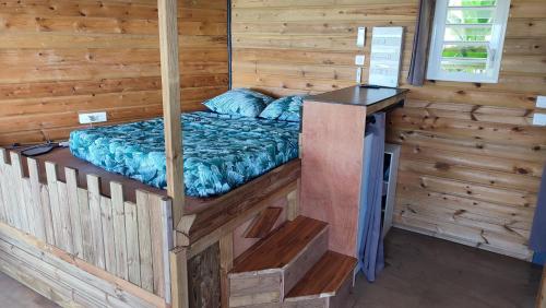 1 cama en una cabaña con paredes de madera en Sunset Sapphire, en Case-Pilote