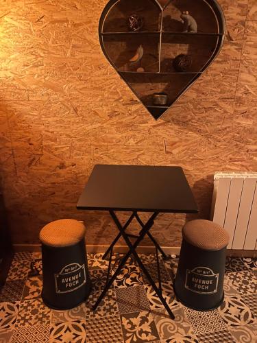 a table and two stools in front of a wall at Logement indépendant la k abane en palette in Blandin
