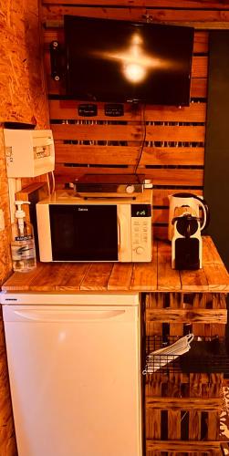a microwave sitting on top of a counter next to a refrigerator at Logement indépendant la k abane en palette in Blandin