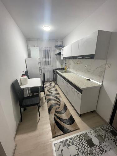 a kitchen with white cabinets and a table and chairs at Apartament 2 camere in Petroşani