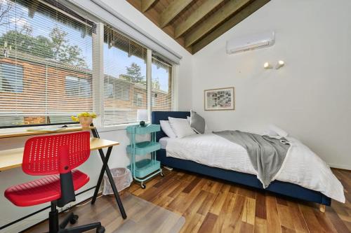 Schlafzimmer mit einem Bett, einem Schreibtisch und einem Stuhl in der Unterkunft Carlton Dream: Leafy 2bed 2bath Lygon Str Townhouse in Melbourne