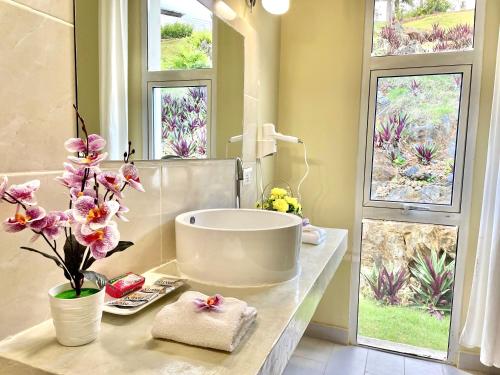 La salle de bains est pourvue d'une baignoire et de fleurs sur un comptoir. dans l'établissement Las Galeras Village Ecolodge, à Las Galeras