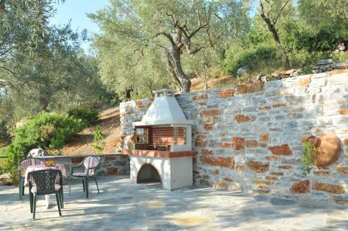 a fireplace in a stone wall with a table and chairs at Violetta Studios & Apartments in Milína