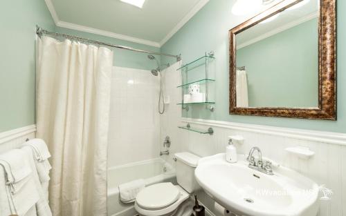 a bathroom with a sink and a toilet and a mirror at The Island Suite at KW Vacation in Key West