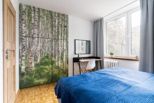 um quarto com uma cama azul e uma grande janela em Verdant Sadyba em Varsóvia