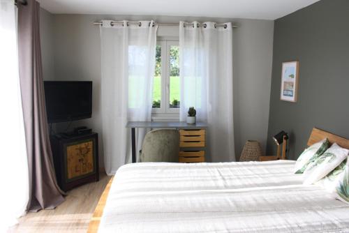 Schlafzimmer mit einem Bett, einem TV und einem Fenster in der Unterkunft Le Mas de la Rocherie Chambre d'hôtes "Référence" in Pihen-lès-Guînes