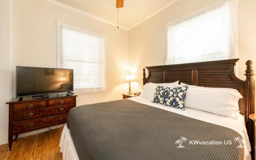 a bedroom with a bed and a flat screen tv at The Island Suite at KW Vacation in Key West