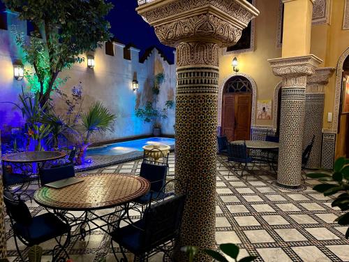 um pátio com uma mesa e cadeiras num edifício em Riad Layalina Fes 7 Chambres & 18 Personnes Piscine, Parking, Vue & Wifi au Pied Medina em Fez