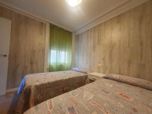 two beds in a room with wooden walls at Salou apartamento familiar / piscina / zona tranquila in Salou