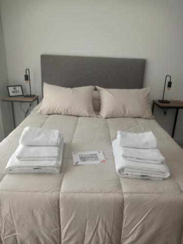 Una cama con toallas blancas encima. en Departamento Parque San Martín en La Plata