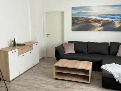 a living room with a black couch and a table at Eine Wohnung zum wohlfühlen in Lübbecke