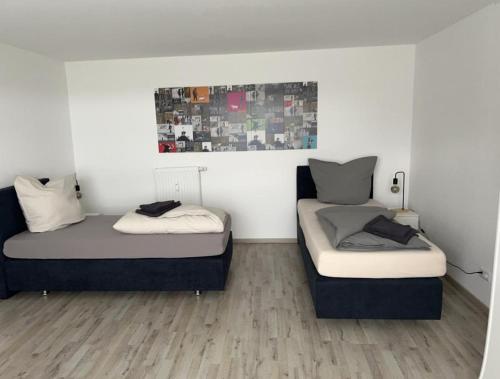 two beds in a room with white walls and wood floors at Eine Wohnung zum wohlfühlen in Lübbecke