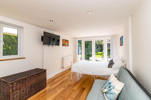 a white bedroom with a bed and a couch at Patio lodge with forest access close to beaches in South Wootton