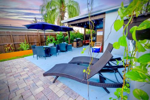 a patio with chairs and tables and an umbrella at Private Heated Pool Oasis Pet-Friendly Retreat Short or long Stays Sleeps 2-8 Ppl in Pompano Beach