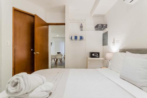 a white bedroom with a bed with towels on it at HotelZone L20 Beach Access in Cancún