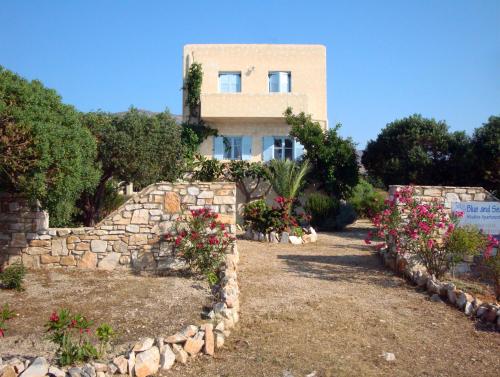 a house with flowers in front of a stone wall at Blue & Sea Studios Apartments in Drios