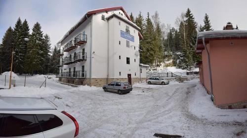 シュチトナにあるOśrodek Wypoczynkowy Pod Skałkąの雪の中の建物の前に停車した車2台