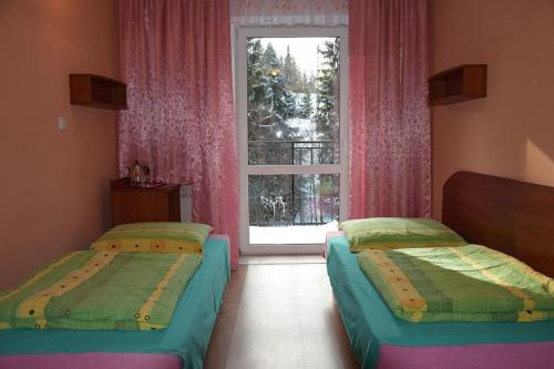 two beds in a room with a window at Ośrodek Wypoczynkowy Pod Skałką in Szczytna