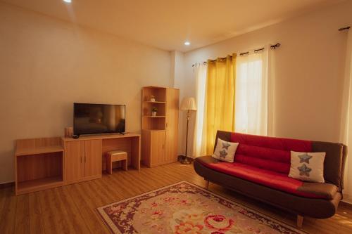 a living room with a red couch and a flat screen tv at July AirBnB in Lower Princeʼs Quarter