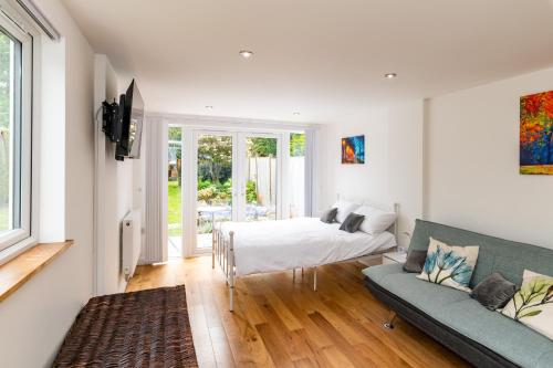 a living room with a couch and a bed at Patio lodge with forest access close to beaches in South Wootton