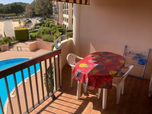 d'un balcon avec une table, des chaises et une piscine. dans l'établissement Appartement 2 chambres avec piscine face à la mer à La Coudouliere, à Six-Fours-les-Plages