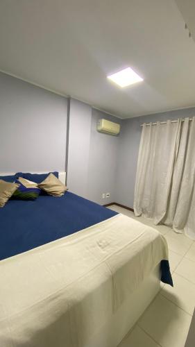 a bedroom with a large bed with a blue blanket at Beach thoow férias in Arraial do Cabo