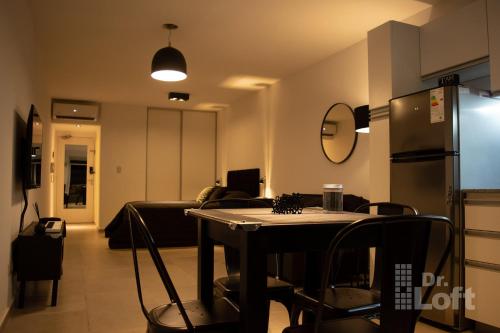 Una sala de estar con una mesa y un refrigerador. en Dr. Loft - Apart céntrico en la ciudad de Rosario, en Rosario