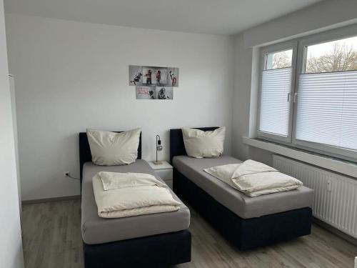 two beds in a room with two windows at Eine modern renovierte Wohnung mit Balkonterrasse. in Lübbecke