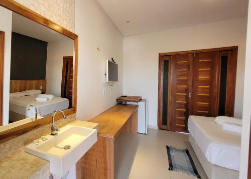 a bathroom with a sink and a bed and a mirror at Pousada Vila Cajuína - Parnaíba in Parnaíba