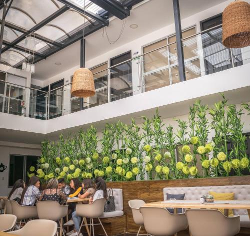 people sitting at tables in a restaurant with a large wall of fruit at Hotel Montes De La Castellana in Armenia