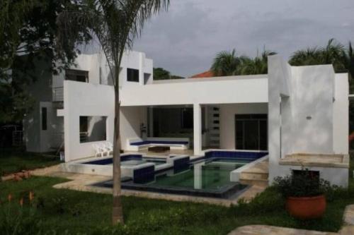 uma casa branca com uma piscina e uma palmeira em Casa Girardot em Ricaurte