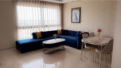 ein Wohnzimmer mit einem blauen Sofa und einem Tisch in der Unterkunft Studio de luxe à casa finance city in Casablanca