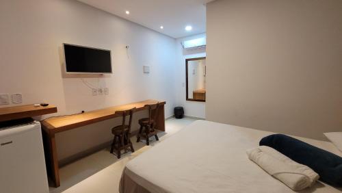 a bedroom with a bed and a desk with a television at Pousada Vila Cajuína - Parnaíba in Parnaíba
