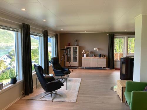 sala de estar con 2 sillas, mesa y ventanas en Fantastic view, quiet and relaxing by the sea en Kvaløya