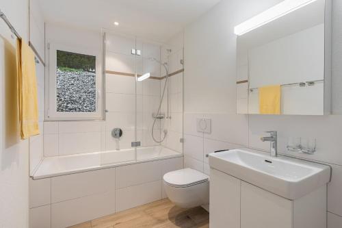 a white bathroom with a sink and a toilet at Melchtal Resort Apart Hotel in Melchtal