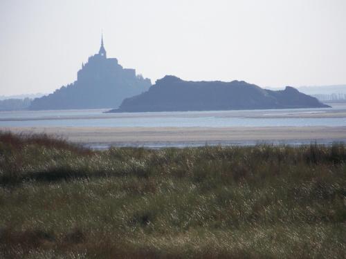 an island in the water with a lighthouse in the distance at Le Domaine de Belleville in Dragey