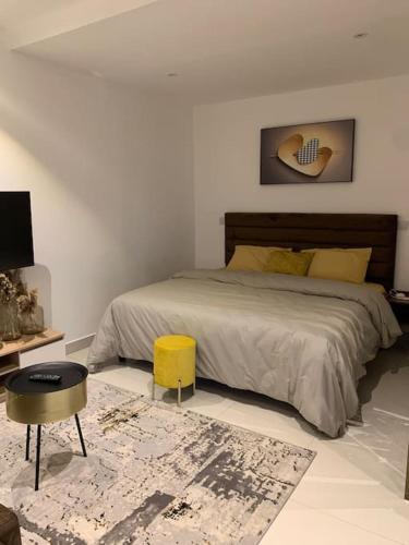 a bedroom with a bed and a yellow stool at The Lennox suite Airport residential Area in Accra