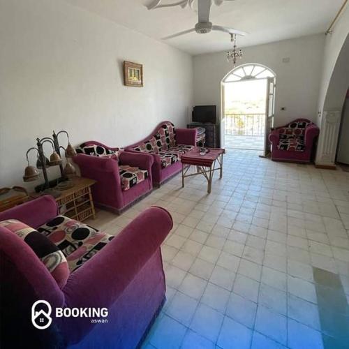 a living room with purple couches and a tile floor at HoneyMoonnaka Guest House Nubian ( بيت هانى ) in Aswan