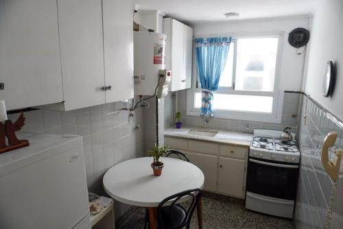 una pequeña cocina blanca con mesa y ventana en Departamento vacacional Mar del Plata en Mar del Plata