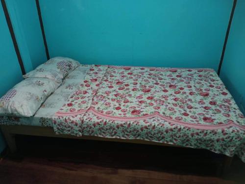 a bed with a floral quilt on top of it at Cambulo Am-way Tavern in Banaue