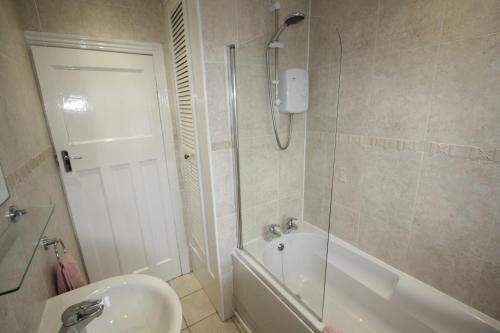 bagno con vasca, lavandino e doccia di Lymm Cottage a Lymm